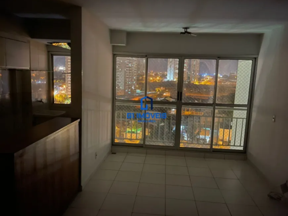 A imagem retrata o interior de um apartamento durante a noite, focando em um espaço que integra cozinha e sala. A iluminação é predominantemente artificial, com o brilho da cidade visível através de uma grande janela dominando o ambiente. Cozinha (Lado Esquerdo): Armários: Os armários são construídos em madeira escura, possivelmente mogno ou um verniz similar. O acabamento parece ser liso, com um certo brilho que reflete a luz. As portas dos armários são de design simples e reto. Pia: A pia é de cerâmica branca ou um material similar de cor clara. A torneira é de metal, provavelmente cromada, e reflete a luz. Há um respingo de azulejos na parede atrás da pia, que parece ser de cor clara e pode ter um padrão discreto. Bancada: Há uma bancada de madeira mais clara, possivelmente pinho ou uma madeira similar, que serve de divisória entre a cozinha e a sala. A madeira da bancada parece ter uma coloração mais clara que os armários. Sala de Estar/Quarto (Lado Direito): Paredes: As paredes são pintadas em um tom claro de branco ou bege. A superfície parece lisa e sem adornos, com exceção de uma tomada ou interruptor visível em uma das paredes. Janela: A janela é o ponto focal do ambiente. É uma grande janela de correr com várias divisórias de metal, provavelmente alumínio pintado de branco ou cinza claro. Há uma grade de proteção de metal do lado de fora da janela, adicionando uma camada de segurança. Uma tela mosquiteira também está presente, indicando a preocupação com insetos. Vista: A vista da janela é um panorama urbano noturno. Edifícios altos com muitas janelas iluminadas se estendem até onde a vista alcança. Há luzes de carros nas ruas e avenidas, criando rastros luminosos. A iluminação da cidade é intensa, contrastando com o céu noturno escuro. Piso: O piso é revestido com azulejos quadrados de cor clara, provavelmente cerâmica ou porcelanato. As juntas entre os azulejos são visíveis, criando um padrão quadriculado. O piso parece limpo e bem conservado. Iluminação: A iluminação interna é fornecida por uma luminária de teto discreta, que parece ser um modelo simples e funcional. A luz é suave e difusa, iluminando o ambiente de maneira uniforme. Detalhes adicionais: É possível notar um objeto no chão, próximo a parede da direita, que pode ser um saco plástico, ou um objeto não identificado. Atmosfera Geral: A atmosfera geral do ambiente é de calma e tranquilidade, com a iluminação suave e a vista da cidade criando um cenário relaxante. A simplicidade do design e a funcionalidade dos móveis sugerem um estilo de vida prático e descomplicado.