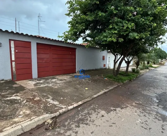 538533134313914 A imagem mostra uma casa térrea com um design simples e funcional. A fachada é pintada em um tom de cinza claro, que contrasta com as portas da garagem, pintadas em um tom vibrante de vermelho. A casa possui um telhado com ondas e é construída em um estilo minimalista, sem muitos detalhes ornamentais. Em frente à casa, há uma área de concreto que serve como entrada e garagem. Esta área parece estar um pouco suja e desgastada, com manchas e pequenas rachaduras. Há também um pequeno jardim com grama e algumas plantas, incluindo uma árvore grande e frondosa que oferece sombra à casa. A rua em frente à casa é asfaltada e apresenta sinais de umidade, sugerindo que pode ter chovido recentemente. No geral, a imagem transmite uma sensação de simplicidade e praticidade, com um toque de cor nas portas da garagem.