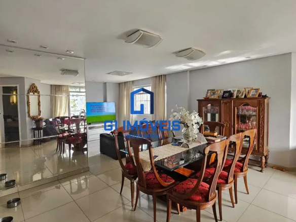 Detalhes Arquitetônicos e Estruturais: Piso: As cerâmicas claras do piso são quadradas e aparentemente de tamanho generoso (talvez 60x60cm ou maiores). As juntas entre as peças são sutis e da mesma cor, criando uma superfície visualmente contínua. O brilho do piso sugere um acabamento esmaltado ou polido. Paredes: A cor cinza-claro das paredes é um tom suave e elegante, quase um "greige" (mistura de cinza e bege), que proporciona um fundo neutro para os móveis e objetos de decoração. A pintura parece ser fosca ou acetinada, sem reflexos excessivos. Teto: O teto branco é liso e uniforme, com luminárias embutidas que se distribuem de maneira estratégica para garantir uma iluminação homogênea. As luminárias têm um design discreto e moderno, com formato retangular e bordas arredondadas. Observa-se também uma abertura quadrada, possivelmente para ventilação ou acesso a instalações. Espelho: A parede espelhada é um elemento marcante do ambiente, criando uma ilusão de profundidade e amplitude. O espelho é composto por grandes placas retangulares, unidas de forma precisa para evitar distorções na imagem refletida. Janelas: As janelas são altas e largas, permitindo a entrada abundante de luz natural. As cortinas claras são de tecido leve e translúcido, como linho ou voile, que suavizam a luz e conferem privacidade ao ambiente. Mobiliário e Decoração: Mesa de Jantar: A mesa tem um design contemporâneo, com tampo de vidro temperado e base escura, possivelmente de metal ou madeira laqueada. O vidro permite visualizar a base da mesa, conferindo leveza e sofisticação ao conjunto. Cadeiras: As cadeiras são um destaque à parte, com sua estrutura de madeira maciça e entalhes delicados. O tecido vermelho com estampas nos assentos adiciona um toque de cor e personalidade ao ambiente. O formato do encosto, com suas curvas suaves, sugere conforto e ergonomia. Buffet/Cristaleira: O móvel de madeira escura é uma peça clássica e imponente, com portas de vidro que revelam a louça e os objetos de decoração em seu interior. As prateleiras internas são iluminadas, valorizando os itens expostos. Sobre o móvel, os porta-retratos com fotos emolduradas criam um ambiente acolhedor e familiar. Sofá: O sofá escuro é de couro ou material similar, com um design clean e minimalista. As almofadas sobre o sofá são de cores neutras e texturas variadas, adicionando conforto e estilo ao conjunto. Televisão: A televisão de tela plana é fixada na parede, otimizando o espaço e proporcionando uma experiência de visualização imersiva. Espelho com Moldura: O espelho com moldura dourada é uma peça decorativa clássica e elegante, que reflete a luz e adiciona um toque de glamour ao ambiente. A moldura é ornamentada com detalhes em relevo, conferindo um ar vintage ao espelho. Arranjo Floral: Um arranjo floral com flores brancas e folhagens verdes adorna o centro da mesa de jantar, adicionando frescor e vida ao ambiente. O vaso é de vidro transparente, permitindo visualizar a água e os caules das flores. Caminho de Mesa: O caminho de mesa claro com detalhes em crochê adiciona um toque artesanal e delicado à decoração da mesa de jantar. O crochê é feito com fios finos e delicados, criando um padrão elegante e sofisticado. Objetos Decorativos: Além dos itens mencionados, o ambiente conta com outros objetos decorativos, como vasos, esculturas e livros, que revelam o estilo pessoal dos moradores e conferem personalidade ao espaço. Outros Detalhes: Próximo à parede espelhada, na parte inferior, há o que parece ser uma série de pequenos comedouros para animais de estimação (provavelmente gatos), indicando a presença de pets na residência. A riqueza de detalhes na imagem revela um ambiente cuidadosamente decorado e planejado, onde cada elemento contribui para criar uma atmosfera acolhedora, elegante e funcional.