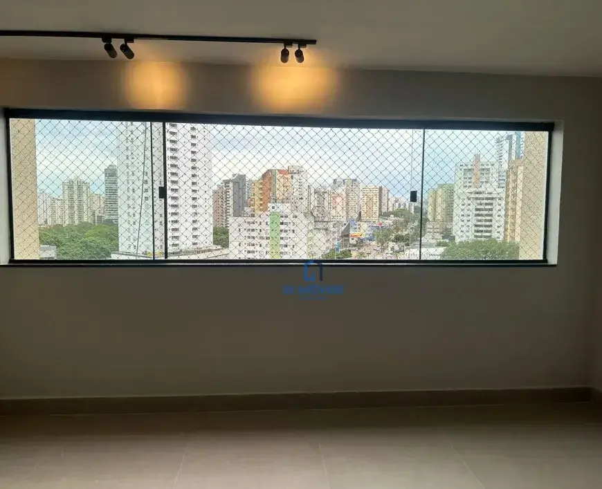 Janela e Vista: Detalhes da Tela de Proteção: A tela de proteção é composta por uma malha fina de fios, possivelmente de nylon ou material similar, entrelaçados em pequenos quadrados. É possível ver os pontos de fixação da tela na moldura da janela, que parecem ser pequenos ganchos ou presilhas discretas. Vidro da Janela: Apesar de a tela ser o foco, é possível notar que o vidro da janela parece ser duplo, o que sugere um bom isolamento acústico e térmico do ambiente. Reflexos sutis no vidro indicam a presença de luz no interior. Céu e Cores da Cidade: Através da tela, o céu aparece levemente nublado, com tons de azul claro e branco acinzentado. Os edifícios da cidade exibem uma variedade de cores, desde o branco e o cinza predominantes até toques de laranja, verde e amarelo em alguns prédios mais baixos. A disposição dos edifícios cria uma sensação de profundidade e perspectiva. Vegetação: A vegetação na parte inferior da vista da cidade é densa e variada, com diferentes tons de verde que indicam a presença de árvores de diferentes espécies. É possível discernir a copa de algumas árvores maiores, o que sugere a existência de parques ou áreas de preservação próximas. Paredes e Piso: Textura da Parede: A pintura das paredes parece ser lisa e uniforme, mas uma análise mais atenta revela uma leve textura, possivelmente resultante da aplicação da tinta com rolo. Essa textura sutil adiciona um toque de interesse visual à superfície. Rodapé Detalhado: O rodapé possui um perfil discreto, com uma pequena saliência que acompanha a base da parede. A junção entre o rodapé e o piso é precisa e bem acabada. Piso Refletivo: O piso de cerâmica ou porcelanato exibe um leve brilho, o que indica que possui uma superfície polida. Essa característica contribui para a sensação de amplitude e luminosidade do ambiente. As juntas entre as placas do piso são finas e regulares, o que demonstra a qualidade da instalação. Iluminação: Spots de Luz: Os spots de luz no trilho do teto são cilíndricos e possuem um acabamento fosco na cor preta. É possível notar que os spots são direcionáveis, o que permite ajustar o foco da luz de acordo com a necessidade. A luz emitida pelos spots é quente e suave, criando uma atmosfera acolhedora. Sombras: As sombras projetadas pelas luminárias no teto e nas paredes adicionam profundidade e dimensão ao ambiente. A luz natural que entra pela janela cria um jogo de luz e sombra que varia ao longo do dia. Detalhes Adicionais: Ausência de Objetos: A ausência de móveis, quadros ou outros objetos de decoração no ambiente chama a atenção para a arquitetura e a vista. Isso sugere que o espaço está recém-construído ou em fase de preparação para ser mobiliado. Sensação de Espaço: A combinação de cores claras, luz natural abundante e a vista panorâmica da cidade cria uma forte sensação de espaço e amplitude no ambiente. A ausência de elementos decorativos reforça essa impressão.