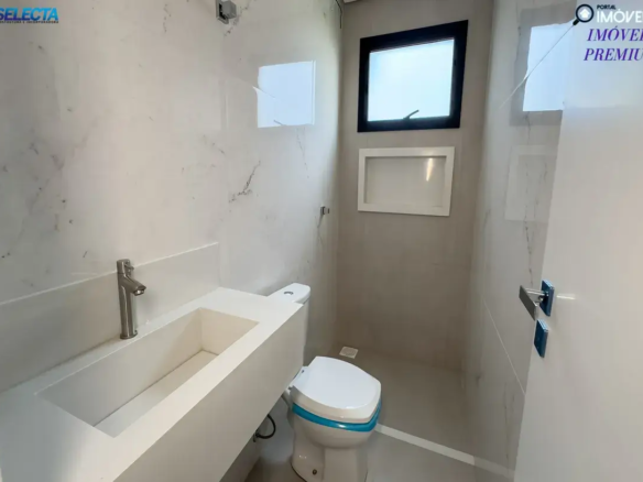 A imagem retrata o banheiro de um apartamento de alto padrão à venda no bairro Santa Mônica, em Uberlândia, MG, evidenciando um ambiente moderno e funcional. O design do banheiro é marcado por uma paleta de cores neutras, como branco e tons de cinza, que criam uma atmosfera clean e sofisticada. A arquitetura apresenta linhas retas e minimalistas, com acabamentos de alta qualidade que reforçam o padrão premium do imóvel. O espaço é bem distribuído, com iluminação natural e artificial que valoriza os detalhes, como revestimentos de primeira linha e metais escovados que conferem um toque de elegância. O banheiro também pode contar com itens modernos, como box de vidro e bancadas amplas, que combinam praticidade e estilo. Localizado no bairro Santa Mônica, um dos mais cobiçados de Uberlândia, o apartamento oferece não apenas um ambiente interno de alto padrão, mas também a conveniência de uma região com infraestrutura completa e qualidade de vida. A imagem reforça a ideia de um imóvel ideal para quem busca conforto, modernidade e uma localização privilegiada.