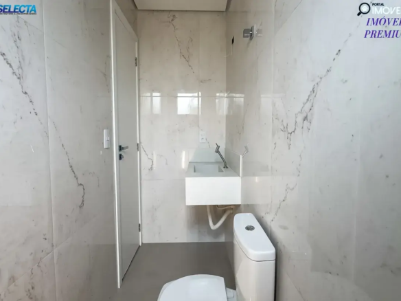 A imagem exibe o banheiro de um apartamento de luxo à venda no bairro Santa Mônica, em Uberlândia, MG, destacando um ambiente moderno e refinado. O design do banheiro é caracterizado por uma combinação de cores neutras, como branco e tons de bege, que criam uma atmosfera serena e acolhedora. A arquitetura apresenta linhas limpas e um layout funcional, com acabamentos de alta qualidade que reforçam o padrão premium do imóvel. O espaço é bem aproveitado, com iluminação natural e artificial que realça os detalhes, como revestimentos de alta qualidade e acessórios modernos, incluindo torneiras e pias de design contemporâneo. O banheiro pode contar com um box de vidro transparente e armários embutidos, que oferecem praticidade sem comprometer o estilo. Situado no bairro Santa Mônica, uma das áreas mais valorizadas de Uberlândia, o apartamento combina um ambiente interno sofisticado com a conveniência de uma localização privilegiada, próxima a comércios, serviços e áreas de lazer. A imagem transmite a ideia de um imóvel perfeito para quem busca conforto, elegância e uma vida equilibrada em um dos bairros mais desejados da cidade.