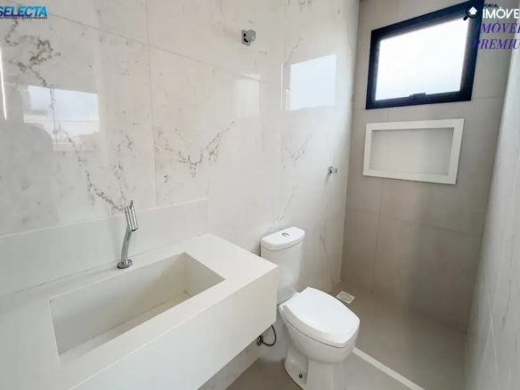 A imagem apresenta o banheiro de um apartamento de alto padrão à venda no bairro Santa Mônica, em Uberlândia, MG, destacando um ambiente moderno e funcional. O design do banheiro é marcado por uma paleta de cores claras, como branco e tons de cinza claro, que criam uma atmosfera luminosa e espaçosa. A arquitetura é caracterizada por linhas simples e elegantes, com acabamentos de alta qualidade que reforçam o padrão premium do imóvel. O espaço é bem distribuído, com iluminação natural e artificial que valoriza os detalhes, como revestimentos de primeira linha e acessórios modernos, incluindo torneiras e pias de design contemporâneo. O banheiro pode contar com um box de vidro transparente e armários embutidos, que oferecem praticidade sem comprometer o estilo. Localizado no bairro Santa Mônica, um dos mais cobiçados de Uberlândia, o apartamento oferece não apenas um ambiente interno de alto padrão, mas também a conveniência de uma região com infraestrutura completa e qualidade de vida. A imagem reforça a ideia de um imóvel ideal para quem busca conforto, modernidade e uma localização privilegiada.