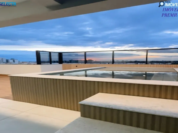 Aqui está uma descrição da imagem: A imagem mostra uma piscina em uma cobertura com vista para um horizonte urbano ao pôr do sol. As cores são dominadas por tons de azul e laranja do céu e pelos tons neutros da piscina e do deque. A piscina é retangular e cercada por uma parede de madeira clara. Uma borda de concreto branco percorre o topo da parede da piscina e um banco de concreto fica na frente da piscina. O piso é de cerâmica clara e contribui para a sensação de limpeza e modernidade. Ao fundo, um horizonte urbano com prédios de vários tamanhos pode ser visto. A vista é parcialmente obstruída por uma barreira de vidro preta que circunda o deck da cobertura. O céu está nublado e o sol está se pondo, criando um brilho laranja no horizonte. A cena geral é de luxo e sofisticação. A piscina e o deque da cobertura oferecem um espaço relaxante e elegante com uma vista deslumbrante da cidade. A paleta de cores é relaxante e convidativa, e os materiais utilizados são de alta qualidade. Palavras-chave: Piscina, cobertura, cidade, horizonte, pôr do sol, luxo, sofisticação, relaxante, elegante, materiais de alta qualidade. cobertura a venda em uberlândia Palavras chave: Cobertura duplex com 4 quartos à venda 185m² no Santa Mônica Cobertura duplex com 4 quartos à venda 180m² no Santa Mônica