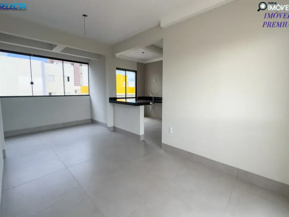 Sala e cozinha integradas com bancada de granito preto. Ambiente moderno, vazio e iluminado com piso cinza e paredes brancas.