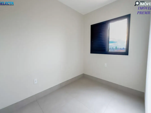 Aqui está uma descrição detalhada da imagem do interior do imóvel: Visão Geral: A imagem apresenta uma sala integrada com a cozinha em um imóvel. O ambiente é novo, com acabamentos modernos e um estilo clean, destacando a luminosidade e o espaço aberto. Arquitetura e Design: Estilo: O design é moderno e minimalista, com foco na funcionalidade e no aproveitamento da luz natural. Cores: Predominam os tons neutros como branco, cinza e preto. As paredes são brancas, o piso é cinza claro e a bancada da cozinha é preta. Sala: A sala é ampla e iluminada por uma grande janela que oferece vista para o exterior. Cozinha Americana: A cozinha é integrada à sala por meio de uma bancada americana revestida em branco com tampo de granito preto. Piso: O piso é revestido com cerâmica ou porcelanato em tom cinza claro, proporcionando um visual clean e moderno. Paredes: As paredes são lisas e pintadas de branco, com pontos de energia bem distribuídos. Ambiente e Características: Estado: O imóvel aparenta ser novo, com acabamentos impecáveis e sem sinais de uso. Vazio: O ambiente está completamente vazio, sem móveis ou eletrodomésticos, permitindo ao futuro morador personalizar o espaço de acordo com suas preferências. Luminosidade: A grande janela proporciona excelente iluminação natural, tornando o ambiente agradável e convidativo. Integração: A integração entre sala e cozinha cria um ambiente social e funcional, ideal para o convívio familiar e para receber amigos. Palavras-chave: Sala integrada com cozinha Cozinha americana Design moderno Estilo minimalista Acabamento clean Luminosidade natural Imóvel novo Apartamento à venda Imóvel para alugar Imóveis premium Bancada de granito preto Observações adicionais: A presença dos logotipos das imobiliárias Selecta e Imóvel Já indica que a propriedade está disponível para venda ou locação. A vista da janela sugere que o imóvel está localizado em uma área urbana, com outros edifícios ao redor. Esta descrição detalhada oferece uma visão completa e informativa do interior do imóvel, destacando seus principais atributos e características, ideal para anúncios imobiliários ou apresentações de propriedades.