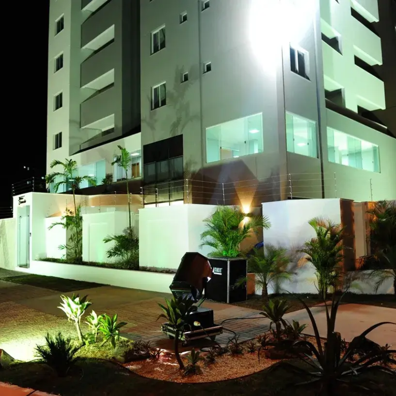 Fachada noturna do Residencial Flor do Cerrado: arquitetura moderna iluminada, paisagismo elegante e design clean.