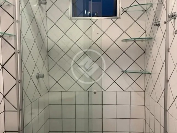 Detalhe do box de vidro do banheiro com revestimento cerâmico branco e prateleiras de vidro no Residencial Hayward.