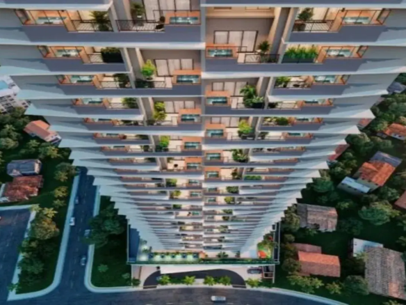 Ok, vamos descrever a imagem detalhadamente: A imagem apresenta uma vista aérea em perspectiva acentuada, olhando de cima para baixo ao longo da fachada de um edifício residencial muito alto e moderno. A perspectiva cria uma sensação de vertigem e destaca a altura imponente do prédio. Detalhes do Imóvel (Edifício): Estrutura e Design: O edifício possui múltiplos andares (um arranha-céu) com uma arquitetura contemporânea. A fachada não é reta, mas sim escalonada ou em degraus, onde cada andar ou conjunto de andares parece ligeiramente deslocado em relação ao inferior/superior, criando um efeito visual dinâmico e texturizado. Cores: A cor predominante da estrutura do edifício é um cinza claro ou branco-acinzentado. As esquadrias das grandes portas de vidro que dão para as varandas e os guarda-corpos parecem ser de um tom escuro, provavelmente preto ou cinza-chumbo. Há também detalhes que parecem ser de madeira clara ou material que imita madeira, visíveis em algumas partes das varandas (possivelmente no piso ou em painéis decorativos/divisórias). Varandas: Cada apartamento possui uma varanda individual. Elas são um elemento central do design. Guarda-corpos: Parecem ser uma combinação de metal escuro com painéis de vidro transparente ou barras verticais finas, garantindo segurança sem obstruir totalmente a vista. Piso: O piso das varandas parece ser claro, talvez cerâmico ou cimentício. Iluminação: A iluminação interna dos apartamentos é visível através das grandes portas de vidro, emitindo uma luz quente e amarelada, sugerindo que a foto foi tirada ao entardecer ou à noite. Algumas varandas também podem ter iluminação própria sutil. Ambiente e Mobiliário (Visível nas Varandas): Móveis: Muitas varandas estão decoradas com móveis de exterior. É possível distinguir pequenas mesas e cadeiras, típicas de conjuntos de bistrô ou áreas de estar compactas. A variedade indica personalização por parte dos moradores. Vegetação: Um detalhe muito relevante é a presença abundante de plantas e flores em vasos em quase todas as varandas. Há vasos de diferentes tamanhos, com plantas de folhagens verdes variadas, algumas mais altas, outras mais baixas, conferindo vida, cor e um aspecto mais natural e acolhedor à fachada predominantemente geométrica e mineral. Ambiente Geral: As luzes acesas e a presença de móveis e plantas sugerem que os apartamentos estão ocupados e as varandas são utilizadas como espaços de convivência e lazer. Entorno: Imediações: O edifício está inserido em uma área urbana, mas com bastante verde. Ao redor da base do prédio, veem-se árvores densas e outras construções mais baixas, principalmente casas com telhados de cerâmica (cor de telha / marrom-avermelhado). Há um contraste nítido entre a escala e modernidade do arranha-céu e as construções vizinhas mais tradicionais. Infraestrutura: Na parte inferior da imagem, são visíveis ruas asfaltadas com alguns carros estacionados e em movimento. Há também calçadas e o acesso à entrada do edifício, que parece ter uma área coberta (porte-cochère) e paisagismo na entrada. Em resumo, a imagem retrata um imponente edifício residencial moderno de cor clara (cinza/branco) com detalhes escuros e em madeira, caracterizado por sua fachada escalonada e varandas individualizadas repletas de plantas. O ambiente combina a verticalidade urbana com a presença significativa de verde, tanto nas varandas quanto no entorno, e a iluminação quente sugere um cenário residencial ao final do dia.