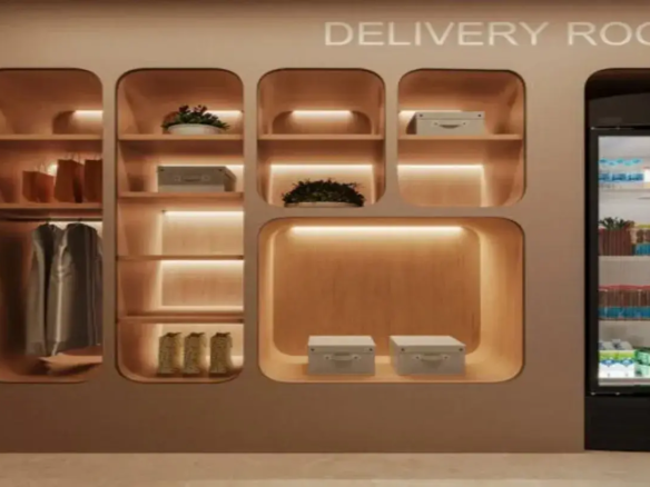 A imagem apresenta um espaço moderno e organizado identificado como "DELIVERY ROOM" (Sala de Entregas), provavelmente localizado na área comum de um edifício residencial ou comercial. Estrutura Principal e Cores: A estrutura principal é uma grande unidade de parede embutida, que combina nichos de armazenamento abertos e um refrigerador. A cor predominante da estrutura externa é um bege ou taupe claro, com um acabamento fosco. Os interiores dos nichos são revestidos com um material que imita madeira clara, criando um contraste suave e acolhedor com a cor externa. O piso visível na parte inferior é de um material claro, possivelmente porcelanato ou concreto polido, em tom neutro. Móveis e Armazenamento: O móvel central é a estante embutida, caracterizada por múltiplos nichos de tamanhos variados, todos com cantos arredondados, conferindo um design suave e contemporâneo. Nichos: Existem vários nichos: Um nicho vertical alto à esquerda, dividido em duas partes: a superior contém sacolas de papel marrons e a inferior possui um varão com algumas peças de roupa penduradas (aparentemente camisas ou casacos em tons neutros/cinza). Uma coluna central com várias prateleiras horizontais. Contém: um vaso branco com uma planta na prateleira superior, uma caixa de armazenamento cinza claro com alça na prateleira abaixo, e na prateleira inferior, o que parecem ser três objetos decorativos ou talvez botas texturizadas em tom claro. Nichos menores, quadrados ou retangulares, localizados na parte superior e central direita. Um deles contém outra planta em vaso branco, e outro contém uma caixa de armazenamento cinza claro idêntica à da coluna central. Um nicho horizontal grande na parte inferior direita, contendo duas caixas de armazenamento cinza claro com alças, lado a lado. Refrigerador: À direita da unidade de nichos, há um refrigerador alto com porta de vidro e moldura preta. Ele parece estar bem abastecido com bebidas (garrafas, caixas de leite/sumo, latas) organizadas nas prateleiras internas. A iluminação interna do refrigerador é mais fria (branca) em contraste com a iluminação quente dos nichos. Iluminação e Ambiente: A iluminação é um destaque no design. A maioria das prateleiras horizontais dentro dos nichos possui fitas de LED embutidas na parte inferior, projetando uma luz quente e indireta para baixo. Isso não só ilumina os objetos armazenados, mas também cria um ambiente acolhedor, sofisticado e convidativo. A iluminação geral do espaço parece suave. Decoração e Detalhes: Além dos itens funcionais (caixas, roupas, bebidas), há elementos decorativos como as plantas em vasos brancos, que adicionam um toque de vida e cor ao ambiente predominantemente neutro. As caixas de armazenamento cinza claro com alças contribuem para a sensação de ordem e padronização. A inscrição "DELIVERY ROOM" em letras brancas, simples e maiúsculas, na parte superior da estrutura, identifica claramente a função do espaço. Impressão Geral: O ambiente transmite uma sensação de modernidade, funcionalidade e organização. A paleta de cores neutras e quentes (bege, madeira clara, cinza claro) combinada com a iluminação indireta e o design de linhas suaves (cantos arredondados) cria um espaço acolhedor e esteticamente agradável, pensado para facilitar o recebimento e armazenamento temporário de entregas de forma prática e elegante.