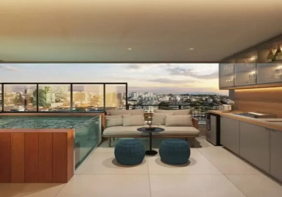 A imagem mostra uma varanda gourmet moderna e sofisticada, provavelmente de um apartamento de alto padrão, com uma vista panorâmica da cidade ao fundo durante o entardecer ou amanhecer. Ambiente e Cores: O ambiente geral é elegante, acolhedor e projetado para lazer e convívio. A paleta de cores é predominantemente neutra e terrosa, com tons de bege, cinza, madeira clara e branco, criando uma atmosfera calma e chique. Pontos de cor mais vibrantes aparecem no azul petróleo dos puffs e no azul-esverdeado da água da piscina/jacuzzi. A iluminação é quente e convidativa, com spots no teto e luz indireta sob os armários da área gourmet, realçando os materiais e criando um clima agradável, especialmente com a luz natural suave vinda da paisagem urbana. Móveis e Estrutura: Piscina/Jacuzzi: No canto esquerdo, destaca-se uma piscina pequena ou uma jacuzzi elevada. Sua lateral externa visível é revestida em madeira ripada vertical de tom médio, quente. As outras paredes são de vidro transparente, permitindo ver a água e adicionando um toque de leveza e modernidade. Área de Estar: Ao centro, há um confortável sofá com estrutura aparente em madeira clara e almofadas grandes e fofas em tecido bege claro ou off-white. À frente do sofá, dois puffs redondos, robustos, revestidos em tecido trançado de cor azul petróleo, servem como assentos adicionais ou apoio. Entre eles e o sofá, uma pequena mesa de apoio redonda com tampo e pé pretos. Área Gourmet/Bar: Na lateral direita, uma bancada funcional se estende pela parede. O tampo parece ser de madeira clara ou material similar. Abaixo da bancada, armários com portas lisas em tom cinza claro ou Fendi. Um frigobar ou adega climatizada em inox está embutido sob a bancada. Acima, armários suspensos com portas de vidro (talvez fosco ou canelado) e molduras finas, onde se podem ver taças e garrafas, sugerindo um bar. A parede atrás da bancada (frontão) é revestida em madeira clara, harmonizando com o tampo. Há iluminação embutida sob os armários superiores, iluminando a área de trabalho da bancada, onde se percebe uma cuba de pia e talvez um pequeno cooktop ou grill. Piso e Teto: O piso é revestido com placas grandes de porcelanato ou material similar em tom bege bem claro ou off-white. O teto é liso, pintado de branco ou cor clara, com iluminação embutida (spots). Vista e Guarda-corpo: Ao fundo, um guarda-corpo de vidro transparente com estrutura metálica preta fina garante a segurança sem obstruir a vista deslumbrante da cidade, com seus prédios iluminados contra um céu de final de tarde com nuvens e tons alaranjados. Em resumo, trata-se de um espaço bem planejado, combinando funcionalidade (área gourmet, piscina) com conforto (área de estar) e estética apurada, ideal para relaxar e receber amigos apreciando a paisagem urbana. Os materiais e cores escolhidos conferem um ar de luxo contemporâneo e atemporal.