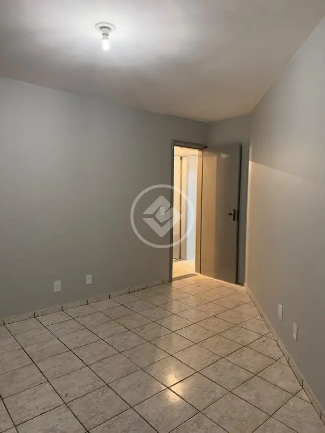 Ângulo do quarto mostrando paredes cinzas, piso frio e porta aberta para o corredor no Residencial Hayward.