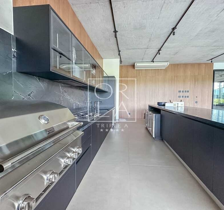 Área de churrasqueira gourmet com acabamento em aço inox e bancada preta.