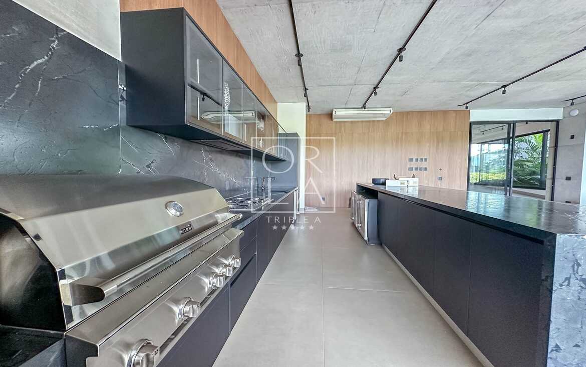 Área de churrasqueira gourmet com acabamento em aço inox e bancada preta.