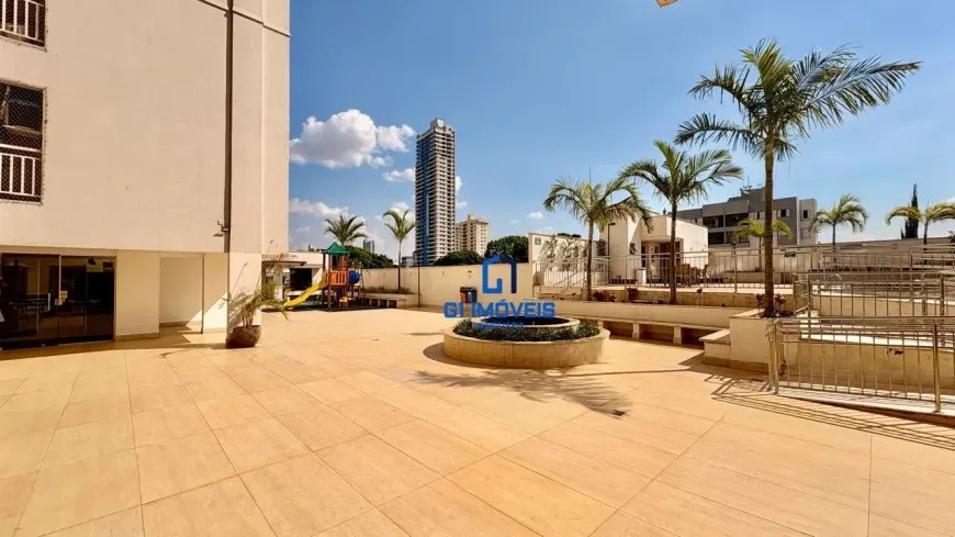 Área comum externa com paisagismo, palmeiras e vista para o skyline urbano no Residencial Auge.