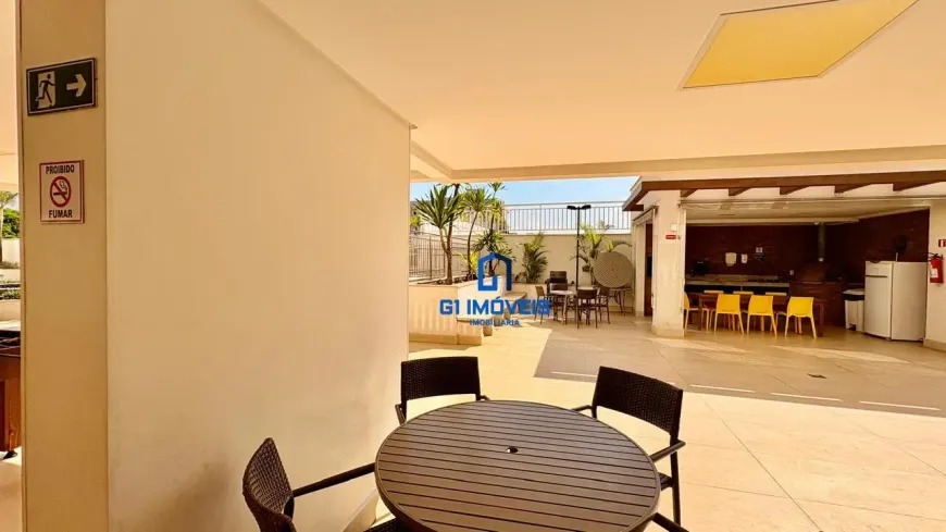 Área gourmet externa coberta com churrasqueira, mesas redondas e cadeiras de vime para eventos sociais.