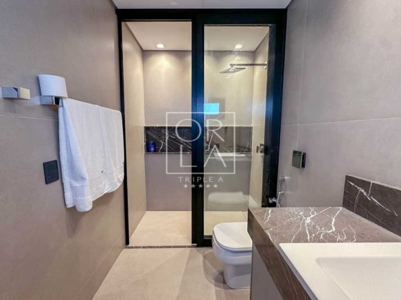 Banheiro moderno com bancada em mármore escuro e cuba de sobrepor branca.