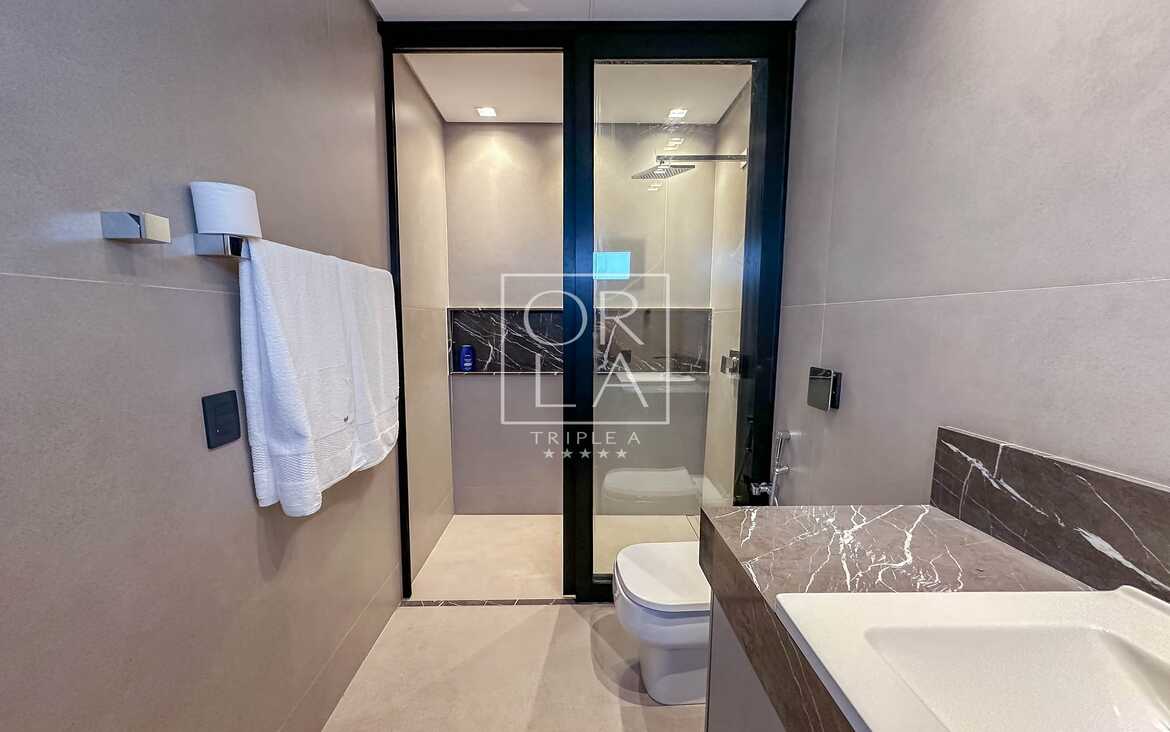 Banheiro moderno com bancada em mármore escuro e cuba de sobrepor branca.