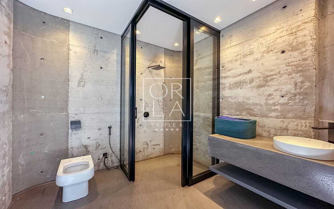 Banheiro moderno com paredes de concreto aparente em imóvel no Aldeia do Vale.