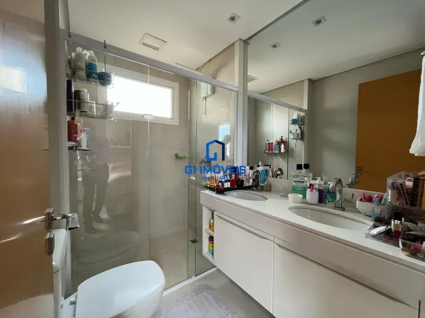 Banheiro moderno com cuba dupla e armários brancos no Maxxi 135.