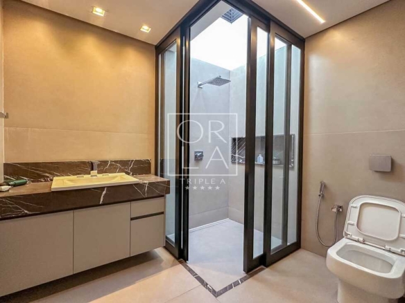 Detalhe de banheiro social com box de vidro e acabamentos premium.