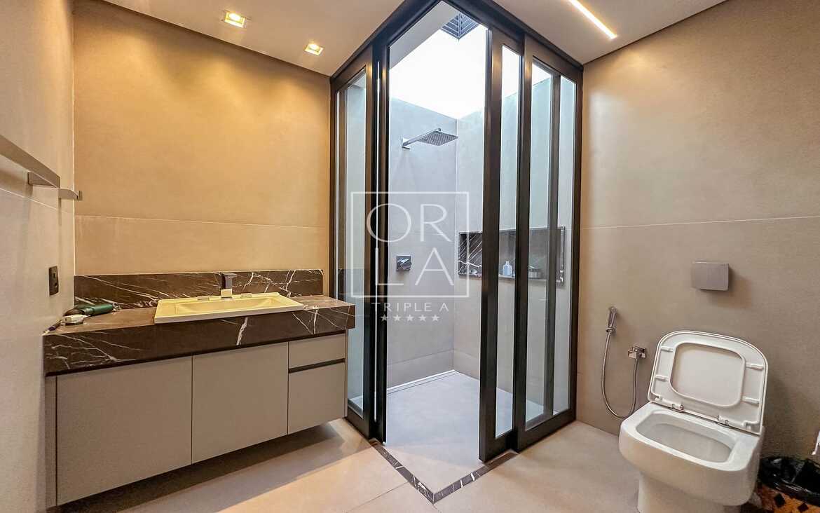 Detalhe de banheiro social com box de vidro e acabamentos premium.