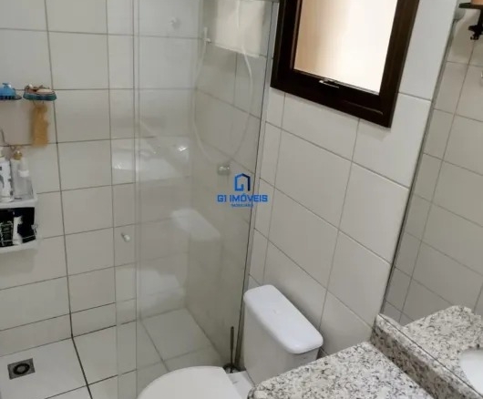 Banheiro social com box de vidro, bancada em granito e revestimento cerâmico branco.