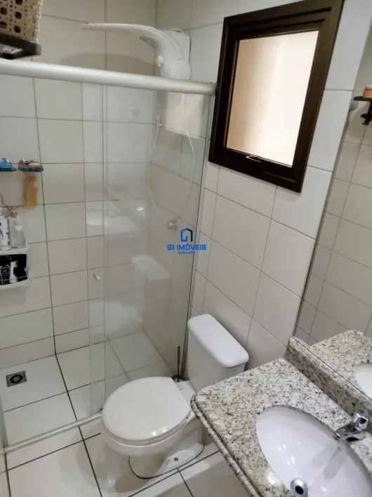 Banheiro social com box de vidro, bancada em granito e revestimento cerâmico branco.