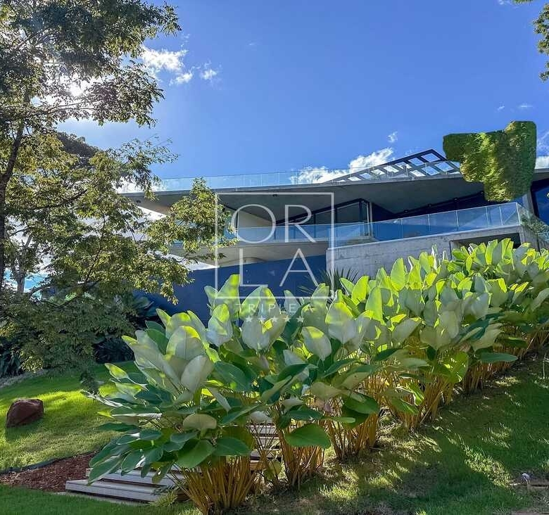 Vista externa de residência contemporânea cercada por natureza preservada.