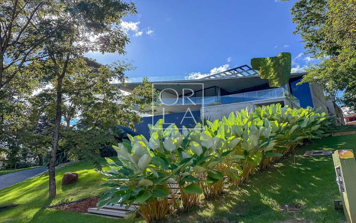 Vista externa de residência contemporânea cercada por natureza preservada.