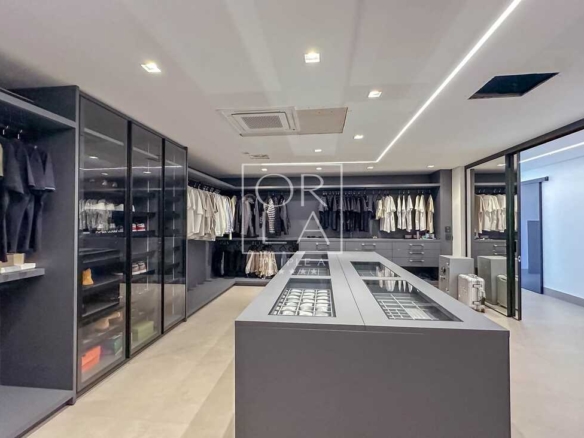 Visão geral de closet de alto padrão com armários em vidro e metal.