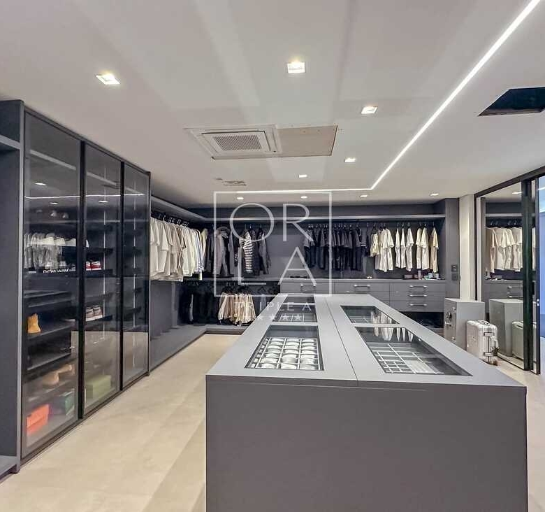 Visão geral de closet de alto padrão com armários em vidro e metal.