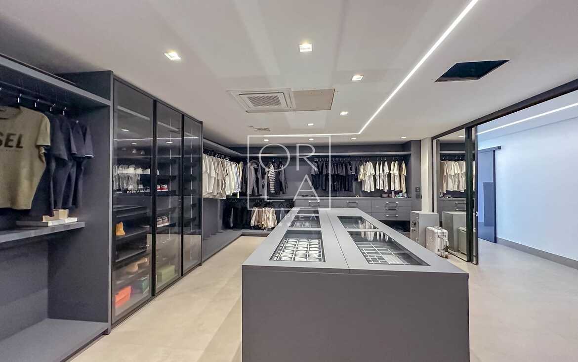 Visão geral de closet de alto padrão com armários em vidro e metal.