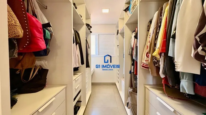 Closet planejado estilo corredor com prateleiras abertas, gaveteiros brancos e organização de roupas e acessórios.