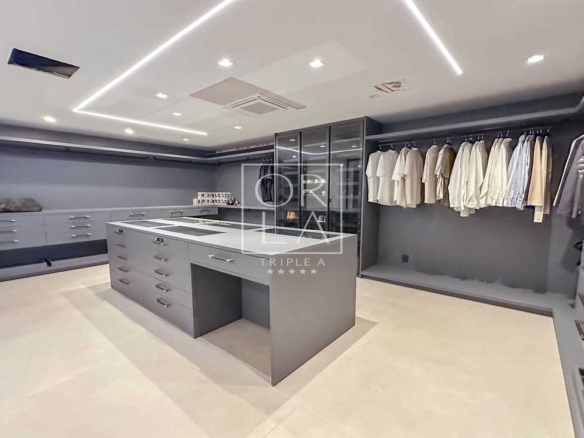 Closet planejado de luxo em tons de cinza com iluminação interna embutida.