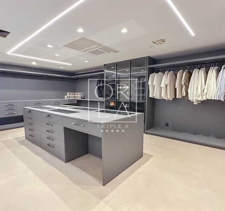 Closet planejado de luxo em tons de cinza com iluminação interna embutida.