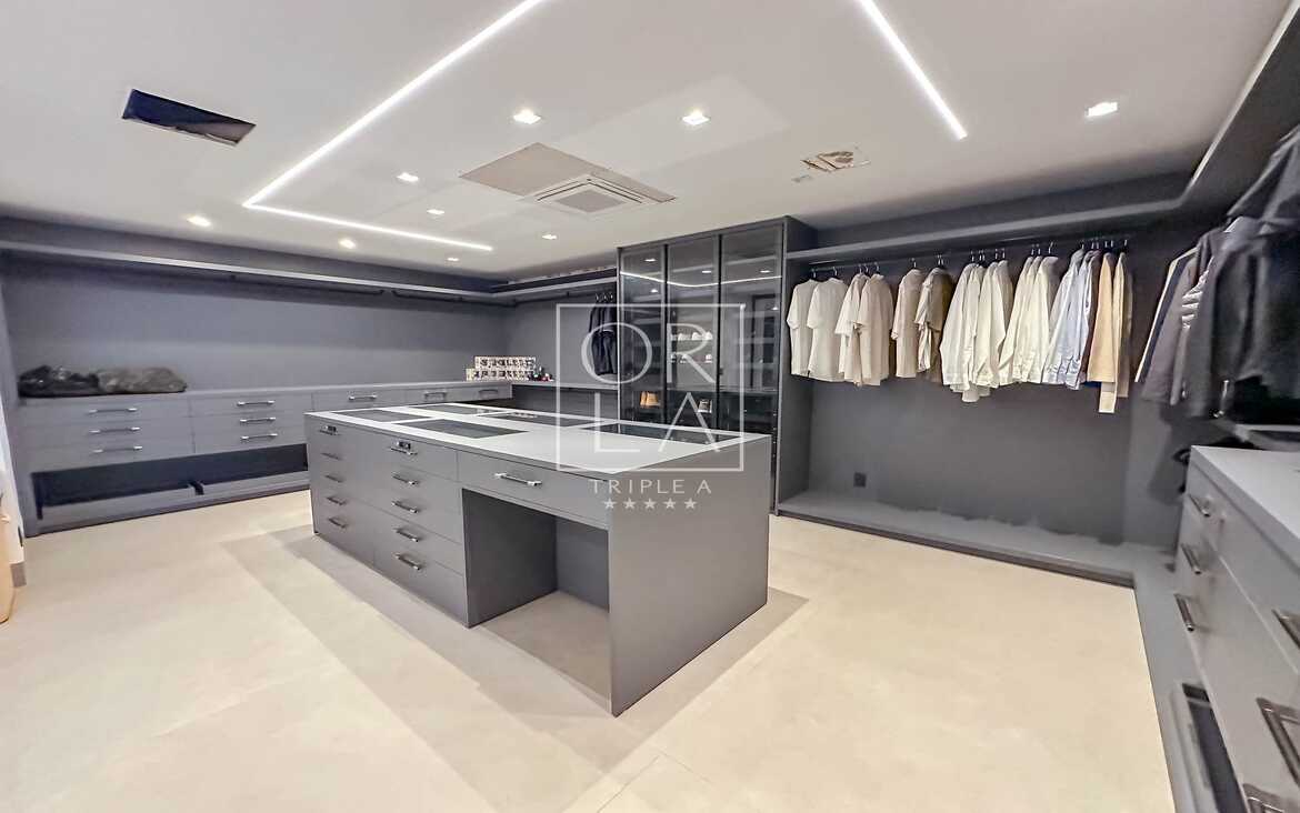 Closet planejado de luxo em tons de cinza com iluminação interna embutida.