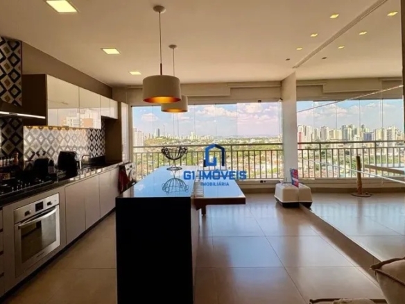 Cozinha com ilha central em granito preto e vista panorâmica para a cidade através da sacada de vidro no Residencial Auge.