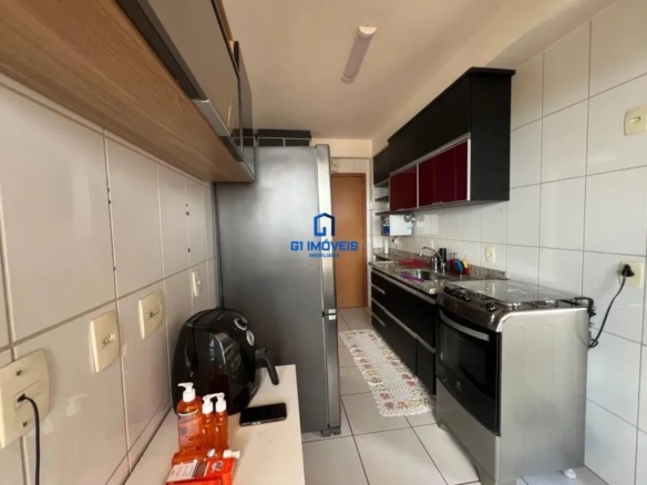 Cozinha moderna com armários pretos e geladeira inox no Condomínio Paysage.