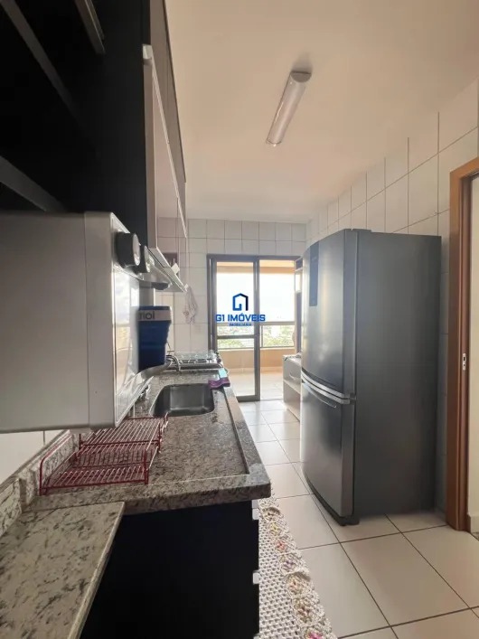 Vista interna da cozinha planejada com pia em granito e eletrodomésticos em inox.