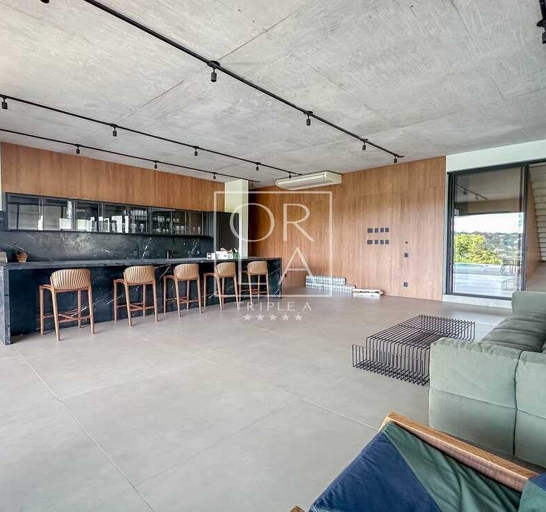 Cozinha integrada com sala em conceito aberto e teto de concreto aparente.