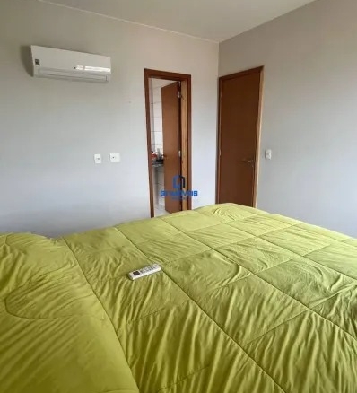 Dormitório com ar-condicionado instalado e cama de casal com edredom verde.