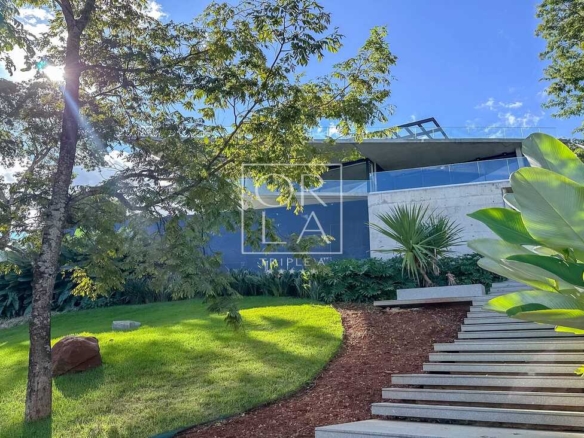 Escada externa em pedra integrada ao jardim e iluminação de balizamento.