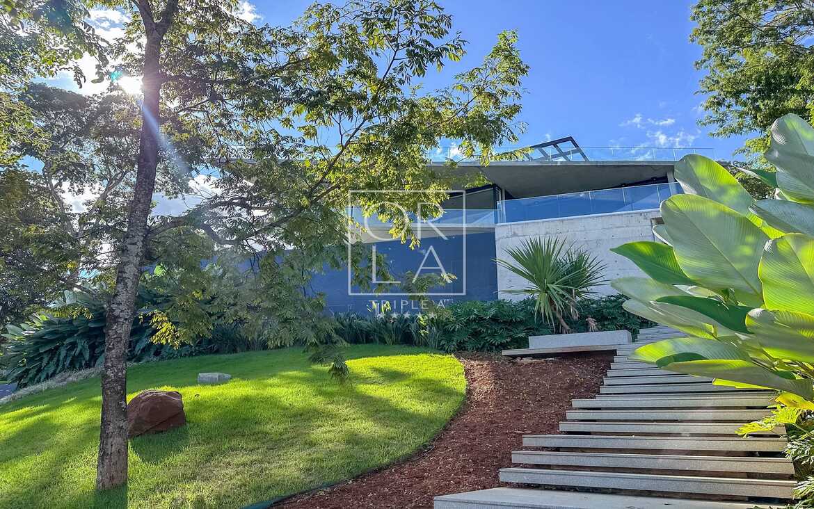 Escada externa em pedra integrada ao jardim e iluminação de balizamento.