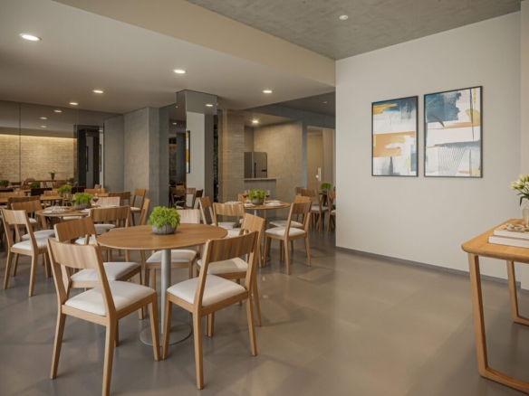 Espaço gourmet com várias mesas redondas de madeira, cadeiras modernas e quadros abstratos na parede.