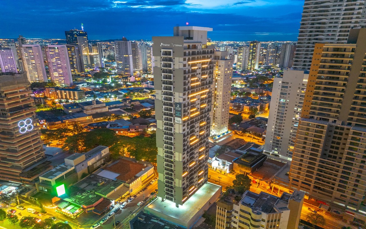 Vista externa noturna do edifício Tempus, destacando a iluminação linear da fachada e a altura do prédio na cidade.