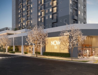 Fachada moderna do empreendimento Now 111 com iluminação noturna, árvores floridas e loja no térreo.
