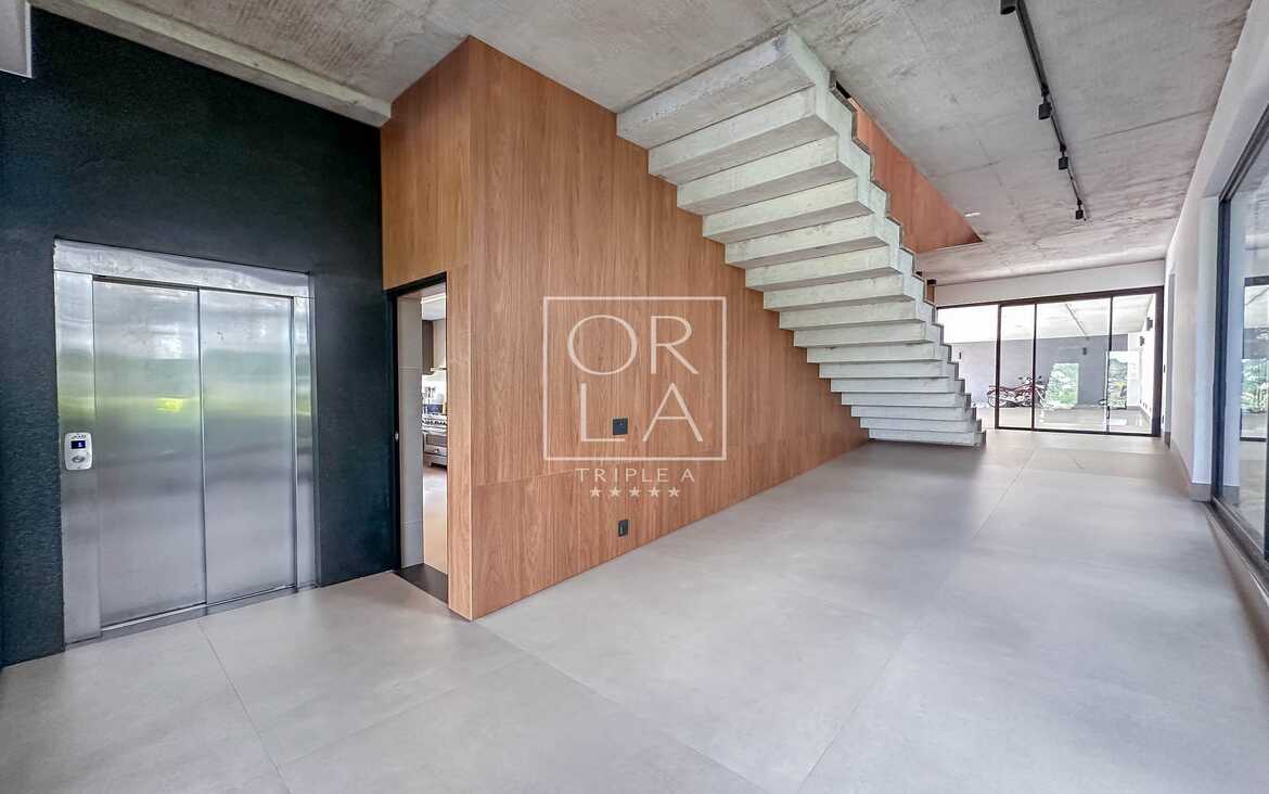 Hall de entrada com elevador privativo e escada de design moderno.