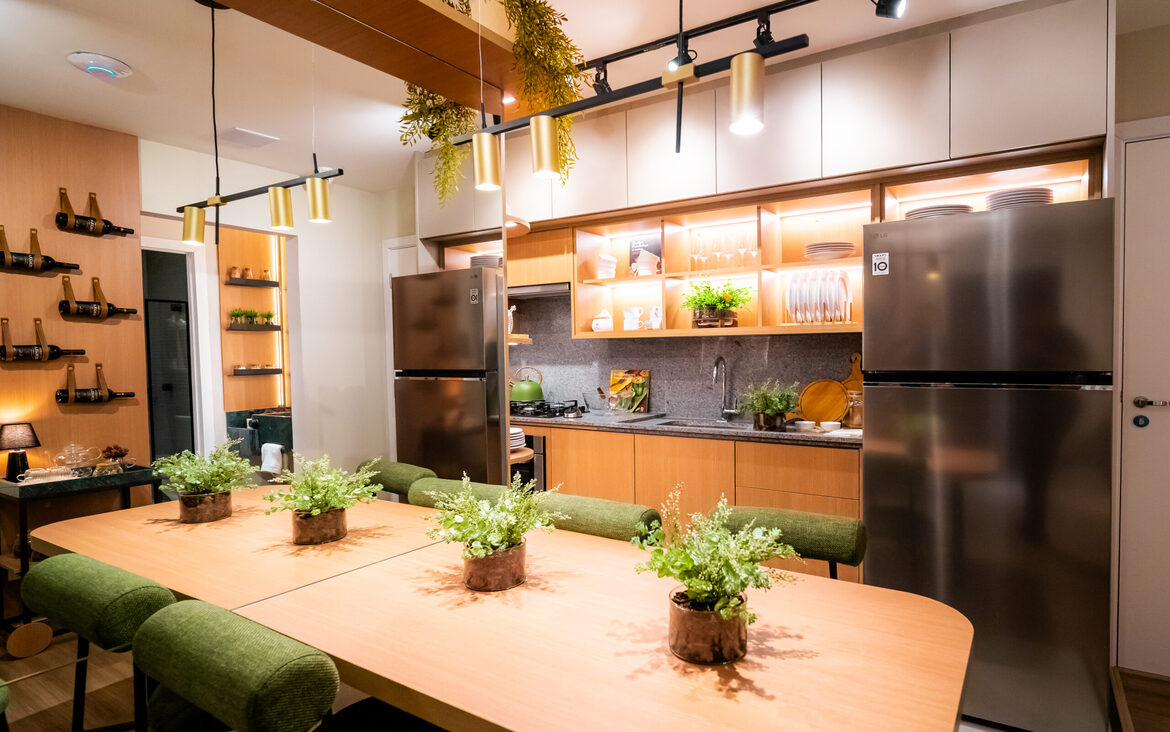 mesa-jantar-cozinha-integrada Mesa de jantar integrada à cozinha com cadeiras verdes, geladeira em inox e iluminação pendente moderna.