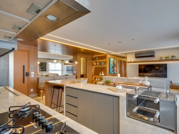 Detalhe de cozinha gourmet com bancada de mármore, cooktop e churrasqueira integrada com acabamento em aço inox.